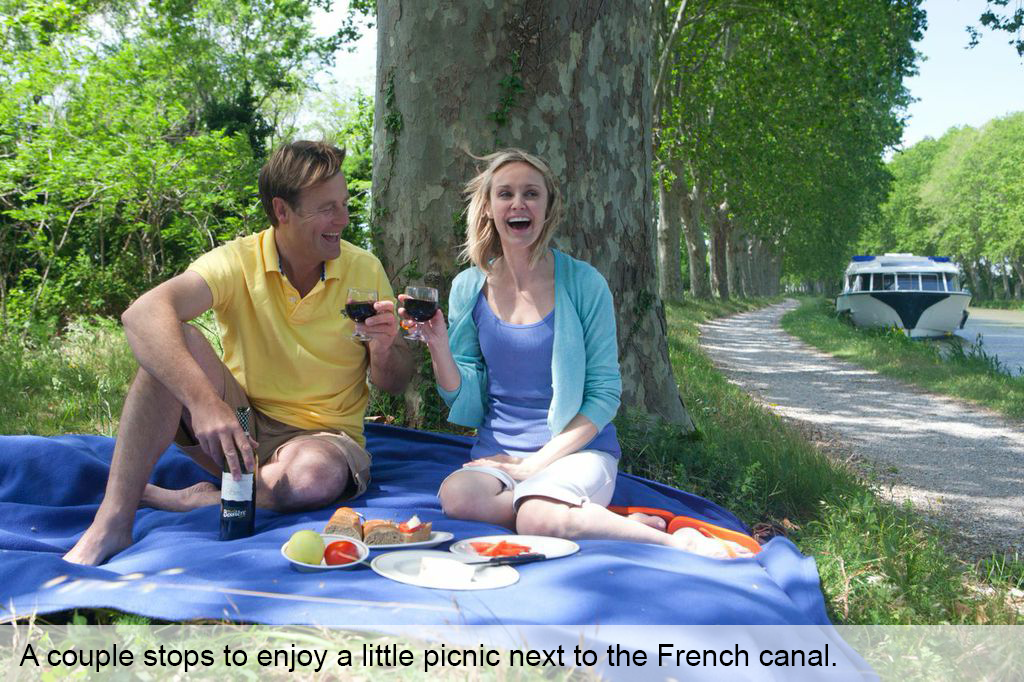 A couple stops to enjoy a little picnic next to the French canal.
