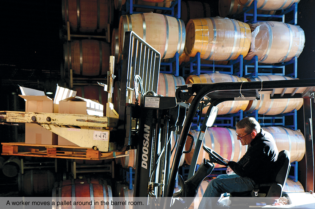 A worker moves a pallet around in the barrel room.